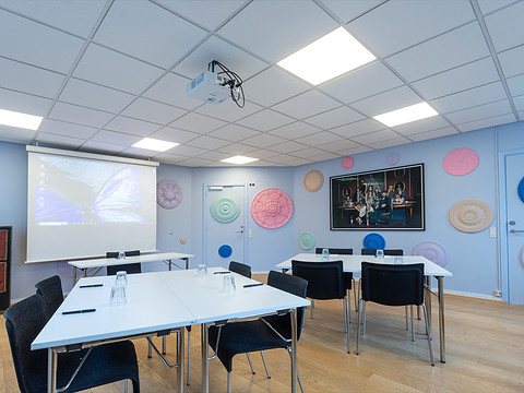 Mødelokale med farverige vægdekorationer og projektor