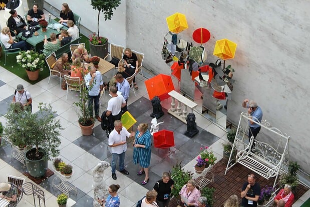 Folk samles i et udendørs mødeområde med kunstinstallationer