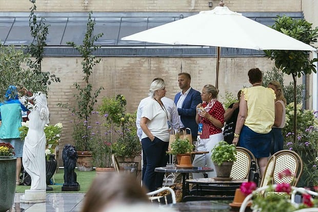 Gruppe mennesker socialiserer i en udendørs have med planter