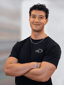 Ung mand står med armene over kors og smiler