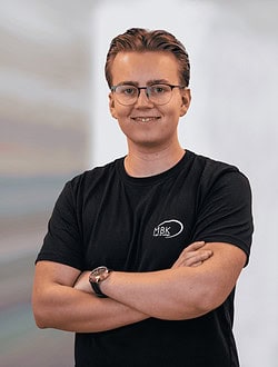 Ung mand står med armene korslagt og smiler