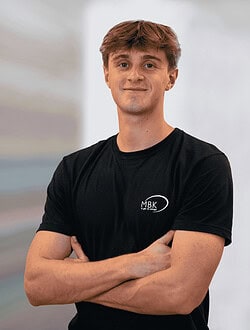 Mand står med krydsede arme og smil i sort t-shirt