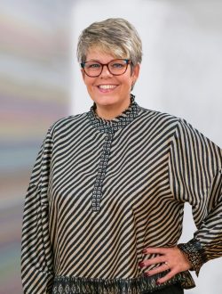 Karina Lauritzen smiler mod kameraet med briller og stribet bluse